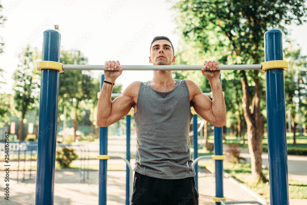 Athlete doing exercise on horizontal bar outdoor Athlete doing exercise on horizontal bar outdoor