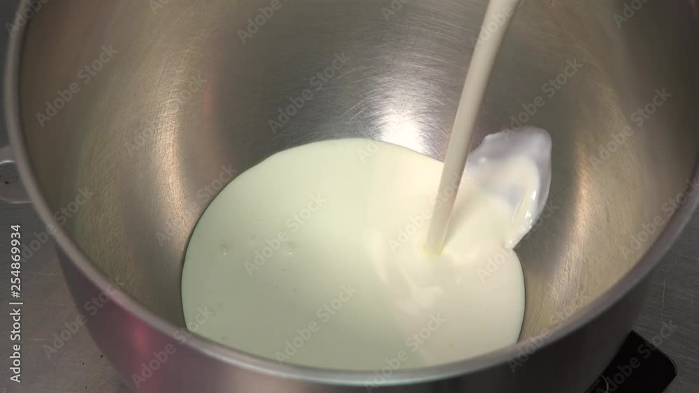 Milk is poured into a metallic bowl - closeup Milk is poured into a metallic bowl - closeup
