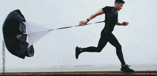 Fototapeta Runner working out using resistance parachute