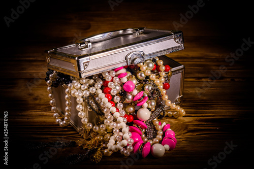 Aluminium case full of different jewelry on wooden table photo