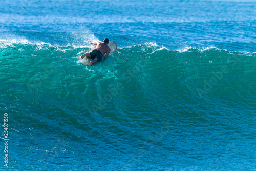 Surfer Surfing Paddles Over Cresting Ocean Wave