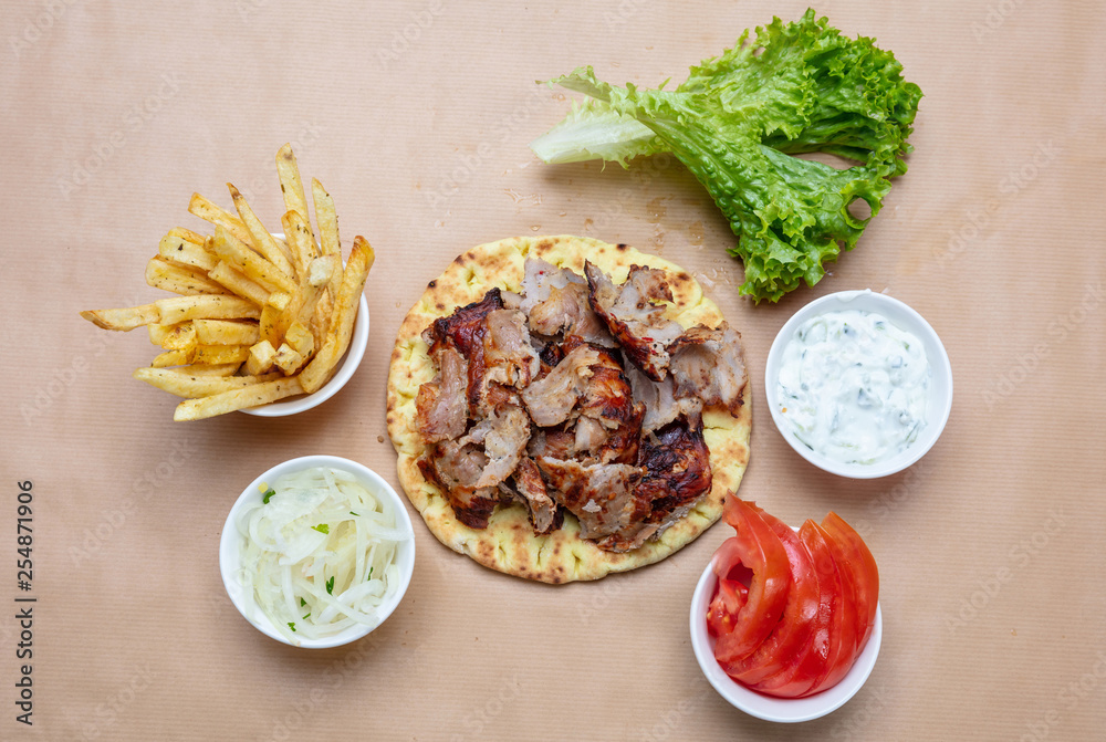 Shawarma, gyros on pita bread, vegetables and tzatziki sauce, top view. Traditional turkish, greek meat food.