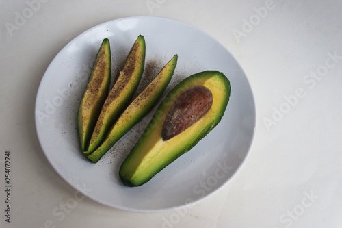 Avocado slices with salt and pepper on a plate. Candid.