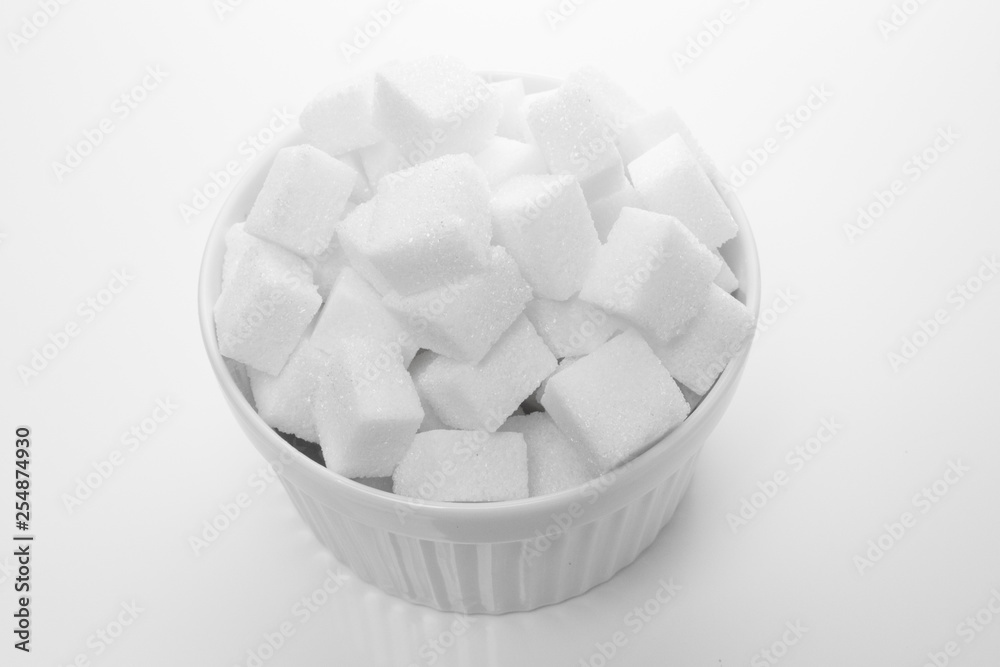 Sliced white sugar in a white bowl on a white background Sliced white sugar in a white bowl on a white background