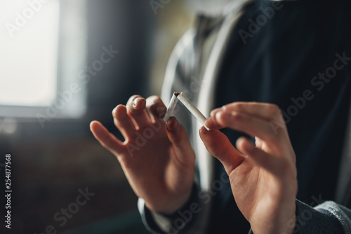 Addicted male person breaks a cigarette