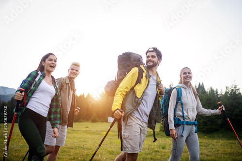 Group of hikers with backpacks and sticks walking on mountain. Friends making an excursion