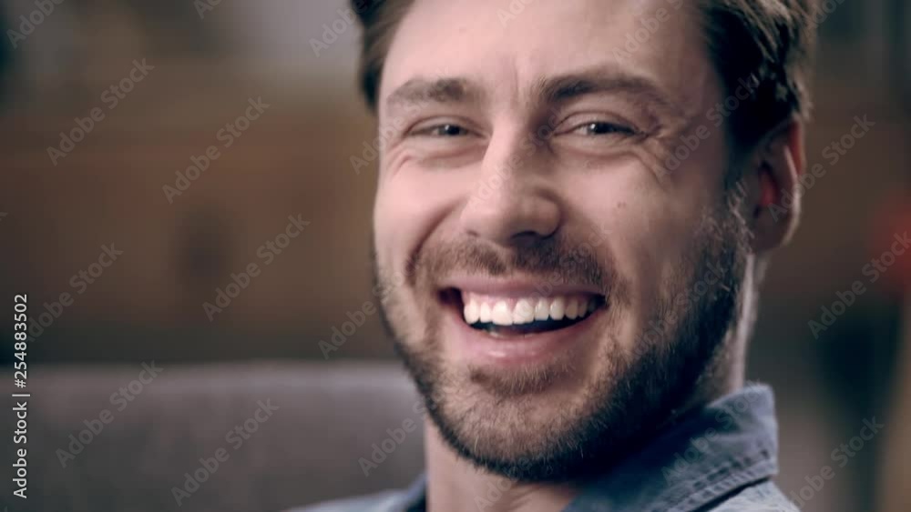 Happy man with beard laughing and blinking while looking at camera Happy man with beard laughing and blinking while looking at camera