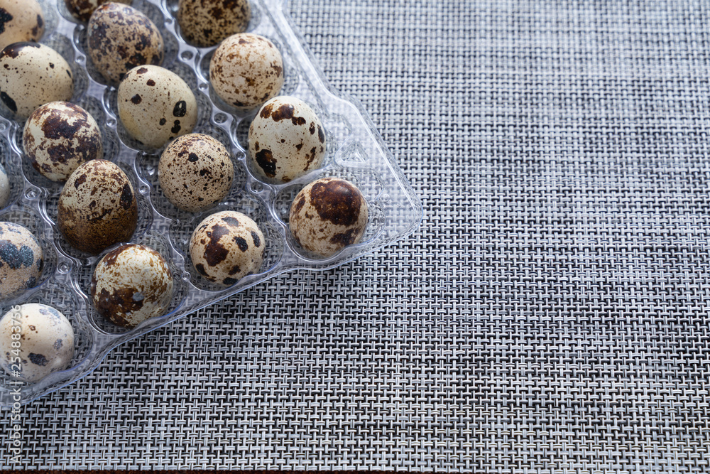 quail eggs in a clear plastic container on a grey cloth table quail eggs in a clear plastic container on a grey cloth table