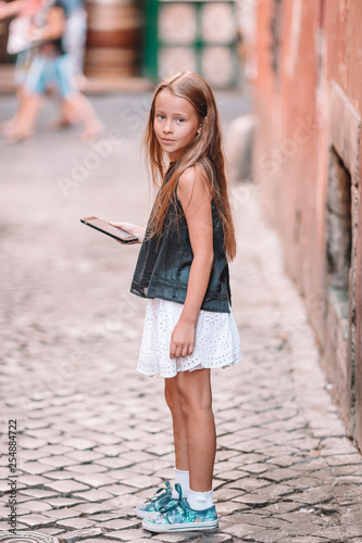 Adorable little girl with cell phone at italian city during summer vacation photo