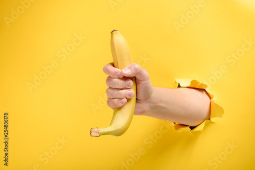 Hand giving a ripe banana Fotobehang