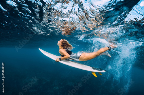 Surfer woman dive underwater. Surfgirl dive under big wave