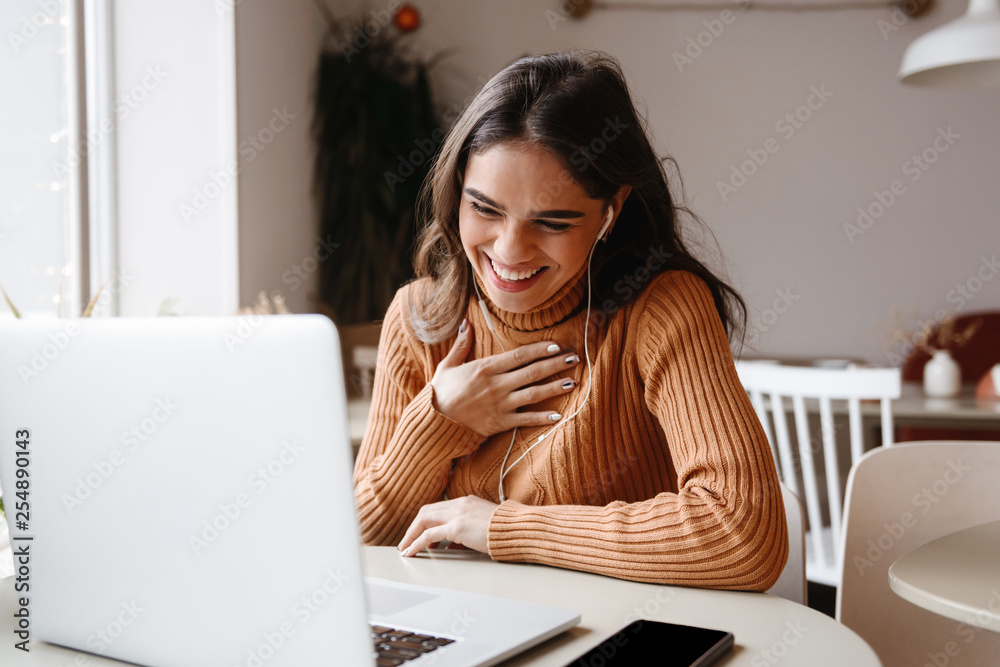 Pretty beautiful woman sitting in cafe indoors using laptop computer. Pretty beautiful woman sitting in cafe indoors using laptop computer.