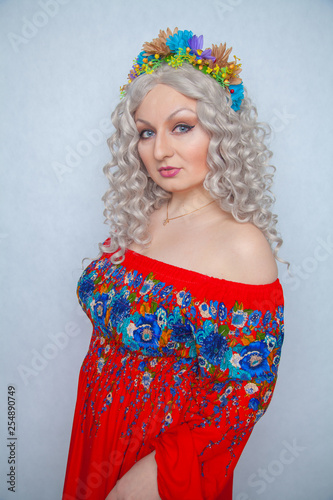 cute chubby girl with flowers in white curly hair in red rustic dress photo