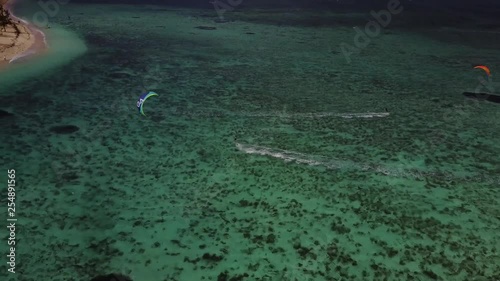 Kitesurfing with green and blue kite towards beach on beautiful paradise island mauritius. Filmed 4K with drone follow cam on a sunny day