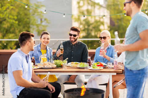 leisure and people concept - happy friends with non alcoholic drinks having bbq party on rooftop in summer