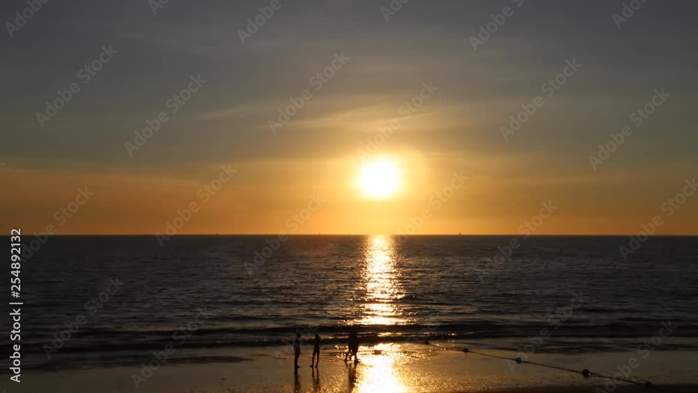 Sunset at the beach with people passing