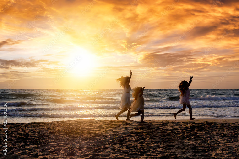 Mutter und ihre Kinder haben Spaß am Strand bei Sonnenuntergang während ihres Sommer Urlaubes