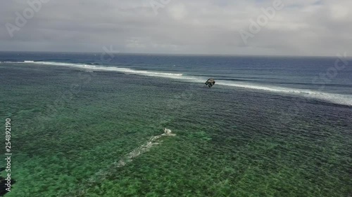 Follow aerial drone cam of kitesurfer freestyle jumping on paradise Island Mauritius. Green and christal clear water on a sunny day with waves in the background