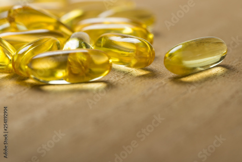Pile of fish oil omega 3 gel capsules on wooden board