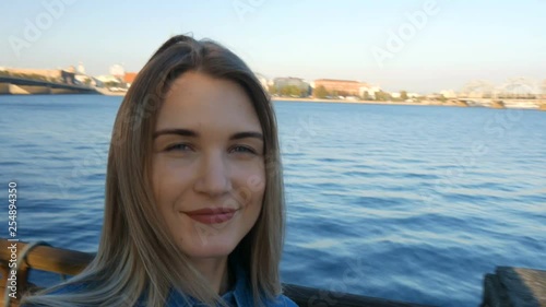 Beautiful lady making a selfie in front of a Riga city panorama at sunset