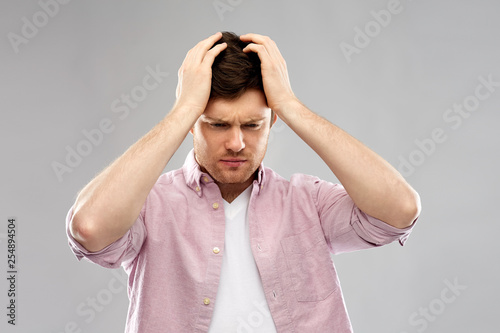 mind, health problem and stress concept - unhappy indian man suffering from headache over grey background
