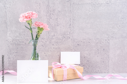 Fototapeta Naklejka Na Ścianę i Meble -  Mothers day handmade giftbox surprise wishes photography - Beautiful blooming carnations with pink ribbon box isolated on gray wallpaper design, close up, copy space, mock up