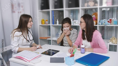 Mother with a cold daughter went to the doctor. Mother brought her teen daughter to the doctor with a headscarf photo