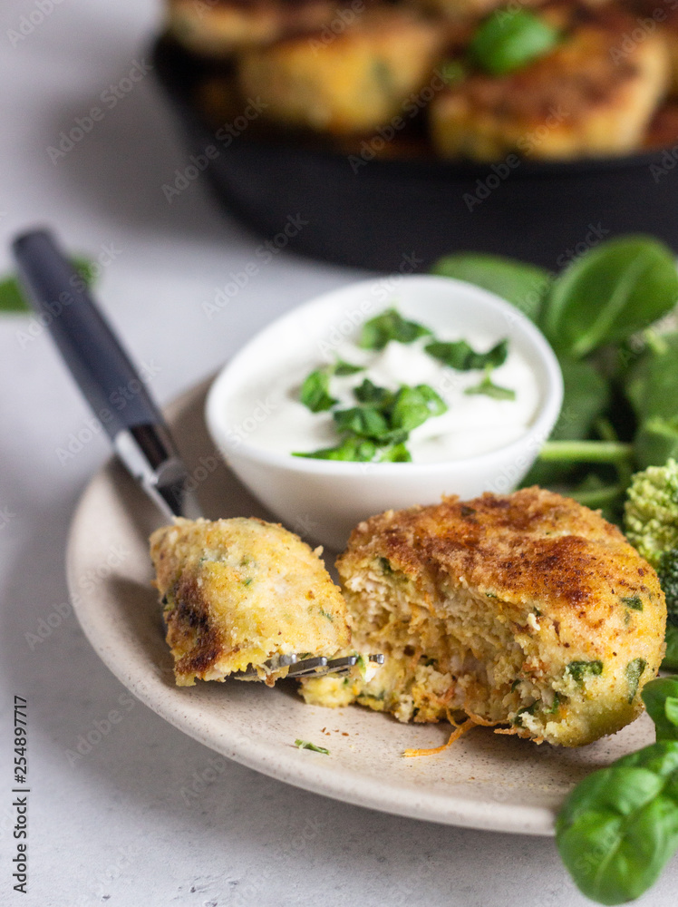 Delicious fried meat cutlets. Chicken or turkey cutlets with carrot and spinach served with broccoli, spinach and sour cream sauce. Light grey concrete background. Delicious fried meat cutlets. Chicken or turkey cutlets with carrot and spinach served with broccoli, spinach and sour cream sauce. Light grey concrete background.