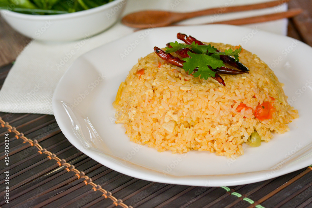Tomato fried rice served with red dried chili in white dish on wooden table. Tomato fried rice served with red dried chili in white dish on wooden table.