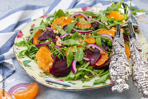 Delicious salad of arugula, tangerines and baked beets close-up.