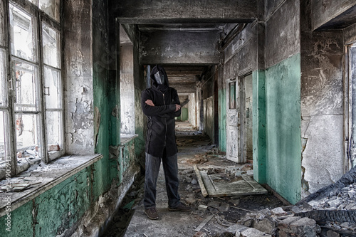 Danger maniac with knife in hand, in leather mask of lague doctor and hood, inside old abandoned house