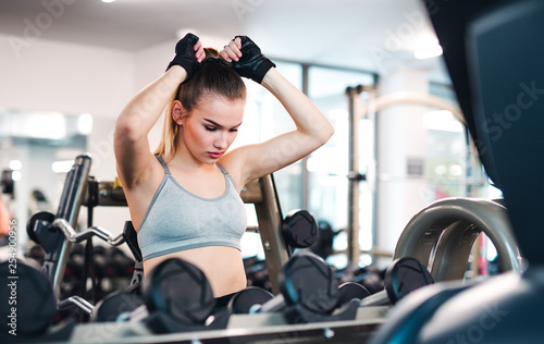 A portrait of young girl or woman doing exercise in a gym.