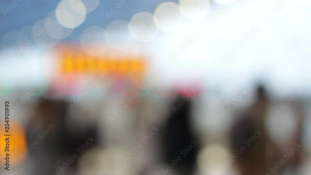 Busy railway station concourse defocused with commuters walking across frame.