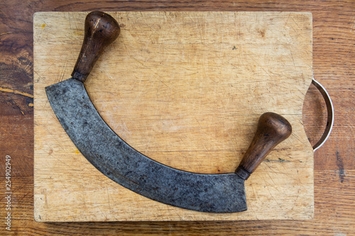 mezzaluna and wooden chopping board