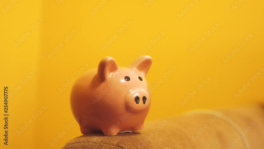 piggy bank business concept. A hand is putting a coin in a piggy bank on a yellow lifestyle background. saving money is an investment for the future. Banking investment and finance concept for your piggy bank business concept. A hand is putting a coin in a piggy bank on a yellow lifestyle background. saving money is an investment for the future. Banking investment and finance concept for your