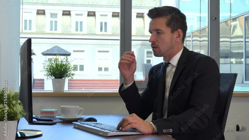 An office worker in a suit in front of a computer gets upset