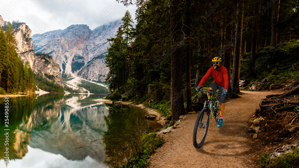 Tourist cycling in Cortina d'Ampezzo, stunning rocky mountains on the background. Man riding MTB enduro flow trail. South Tyrol province of Italy, Dolomites.