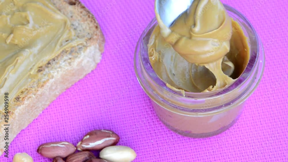 Vídeo do Stock girl making a sandwich. spooning peanut butter out of a jar. Toasted bread with