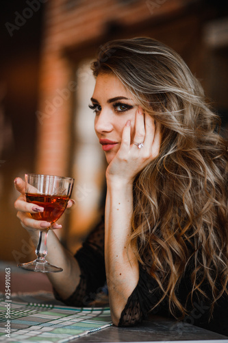 Pretty blonde holds a glass of cognac in her hand