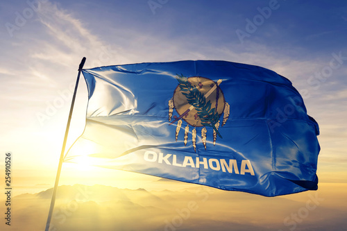 Oklahoma state of United States flag waving on the top sunrise mist fog photo