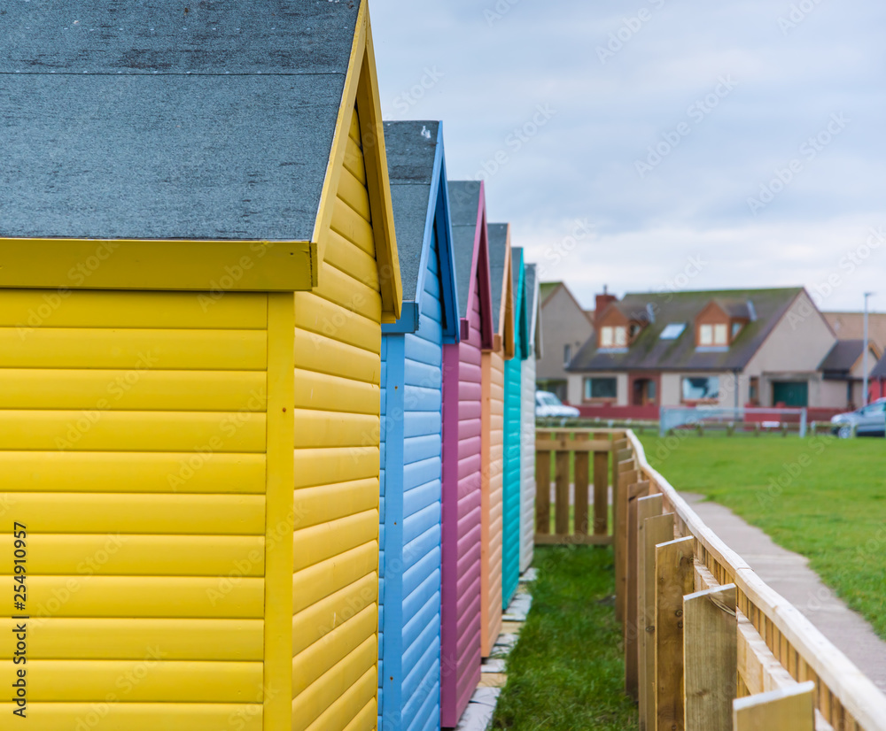 Amble, Northumberland, UK - February 2017: Colourful huts (yellow, blue, pink, green) located close to the beach