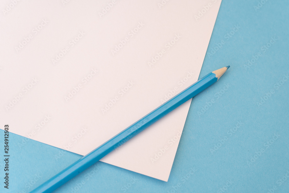 Blue pencil on white piece of paper on blue background. Art, scool or office shoot Blue pencil on white piece of paper on blue background. Art, scool or office shoot