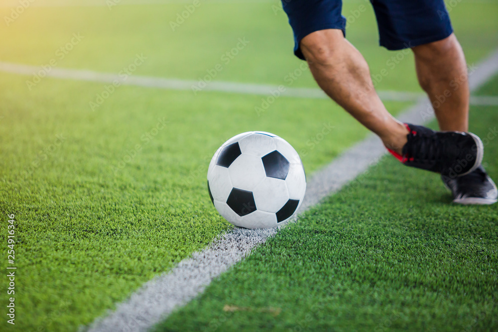 Soccer player speed run to control and shoot ball to goal on artificial turf.