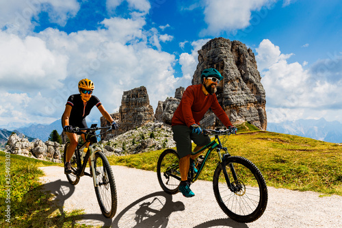 Cycling woman and man riding on bikes in Dolomites mountains landscape. Couple cycling MTB enduro trail track. Outdoor sport activity. photo