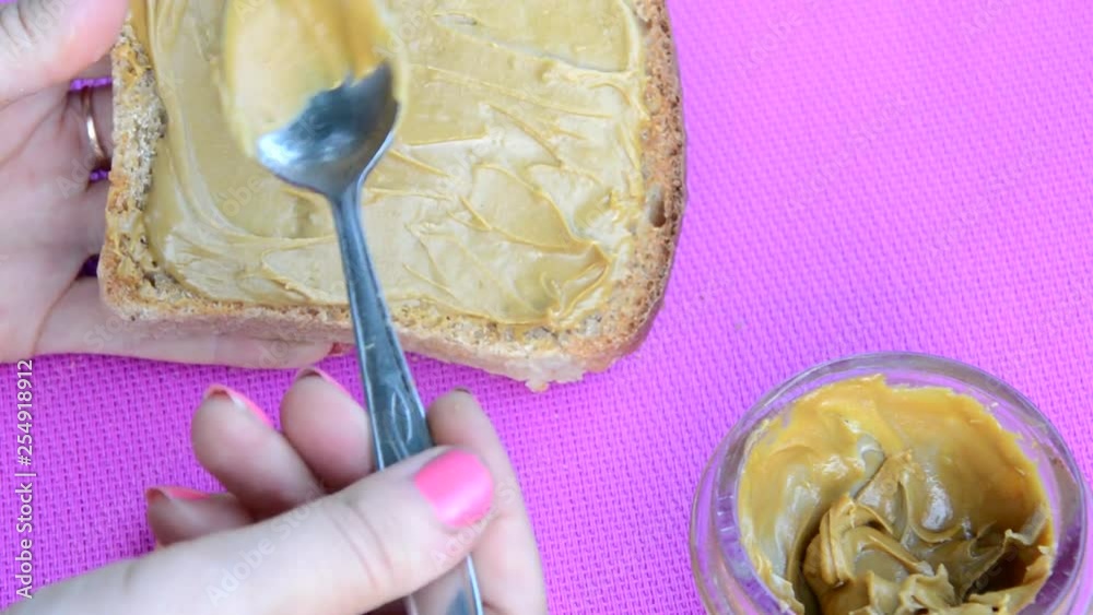 Vídeo do Stock girl making a sandwich. spooning peanut butter out of a
