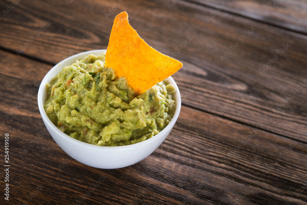 Bowl with guacamole sauce and nachos chips Bowl with guacamole sauce and nachos chips