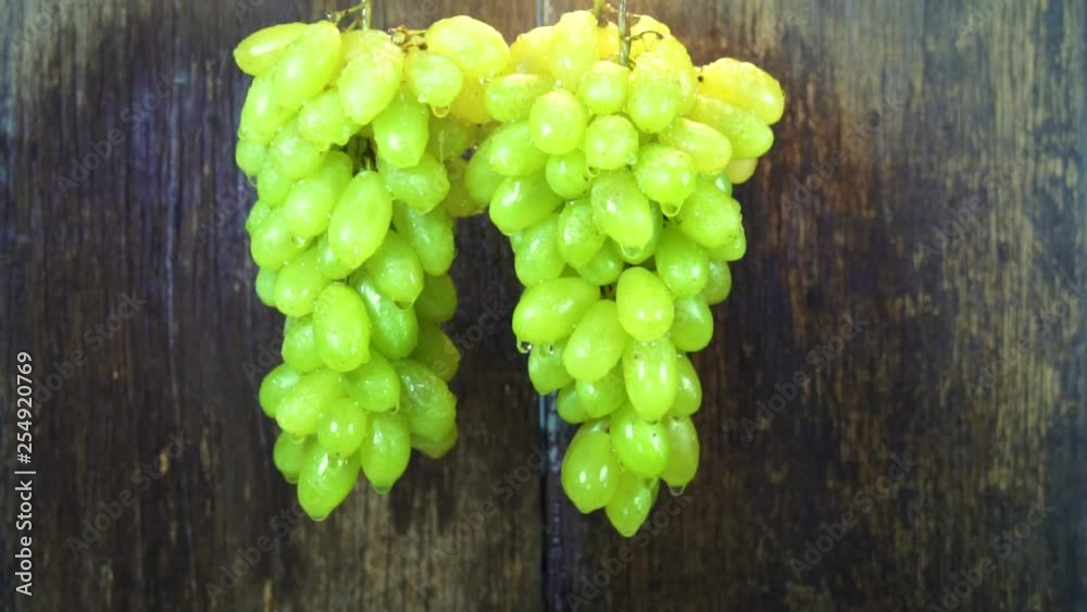 SLOW MOTION: Spay injects water onto a bunch of green grapes. SLOW MOTION: Spay injects water onto a bunch of green grapes.