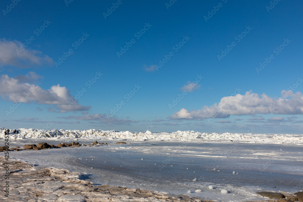 Seaside with frozen and melting ice with rocks