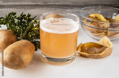 Potato juice in a glass near the whole potato and skarlupa.
