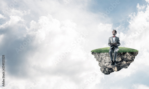 Young businessman or student floating in sky and studying the science © adam121